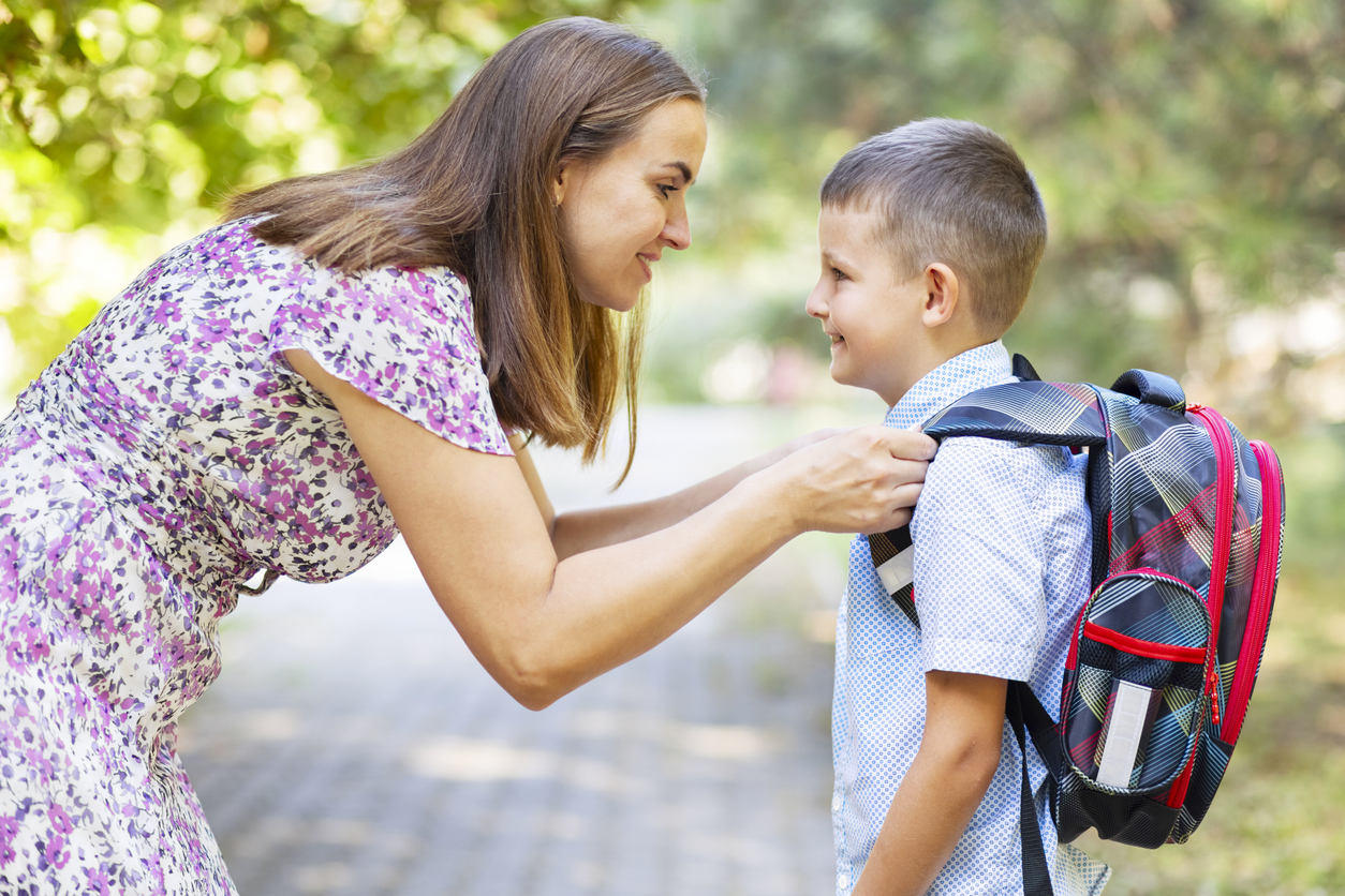 Back to school. Mother saying goodbye to her son as he leave for School. First day at school