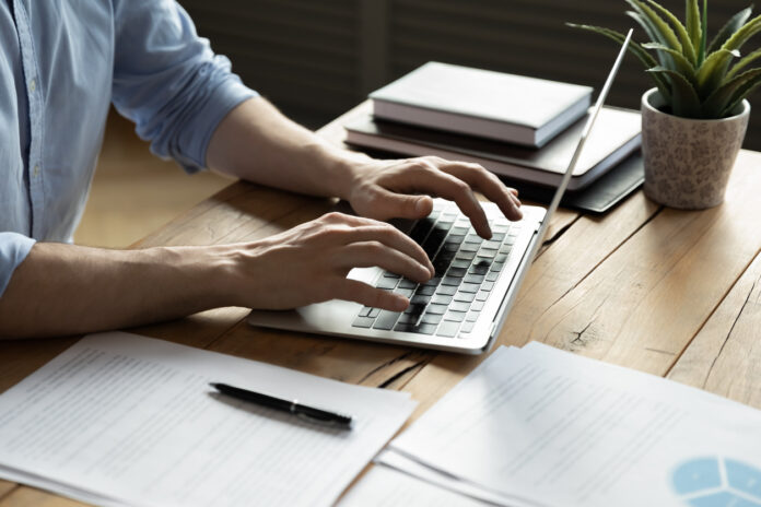 Close up businessman using laptop, sitting at work desk
