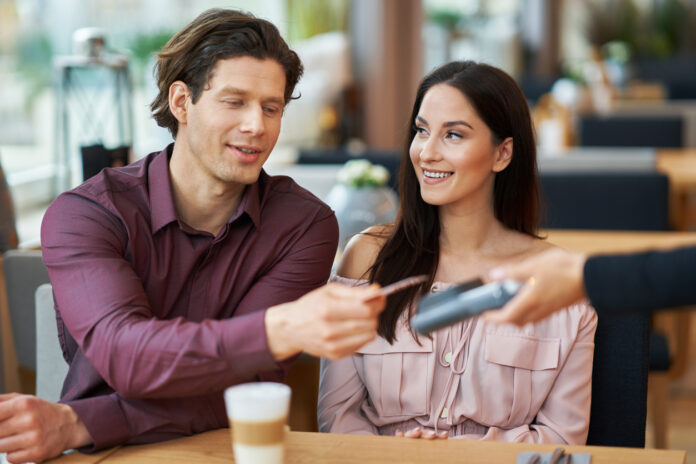 Young Couple paying by credit card in Cafe