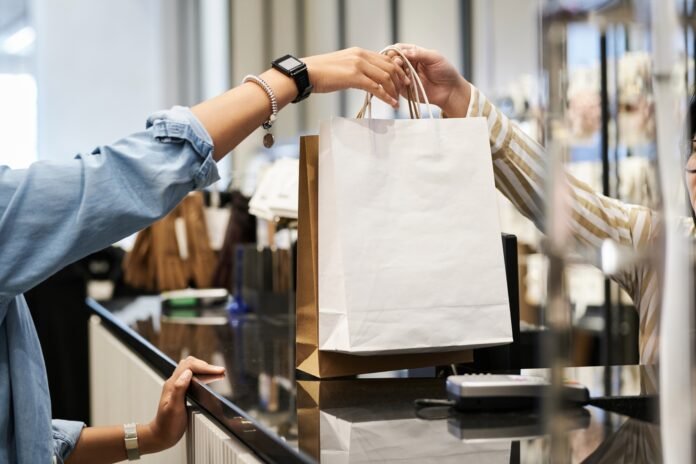 Unrecognizable,Cashier,Giving,Paper,Bags,With,Purchases,To,Unknown,Customer